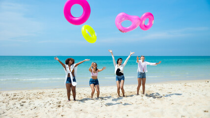 Jumping. Group of teenager girls jump on the beach. Four teenager girl female enjoying on inflatable ring and dance on tropical beach. Vacation trip summer holiday. Gen Z