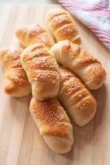 Freshly baked rolls with sesame on a wooden board