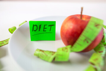 red apple and measuring tape on a plate as a symbol of healthy eating.