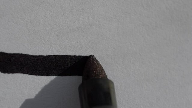 macro close up shot of a black sharpie permanent marker drawing a straight line on a white piece of paper