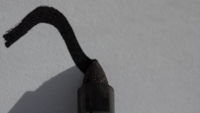 macro close up shot of a black sharpie permanent marker drawing a squiggly curved line on a white piece of paper