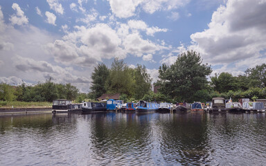 narrowboats moored at a marina on the River Stort near Harlow England with trees and a beautiful sky in the background