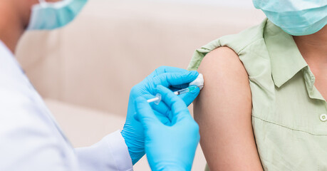Fototapeta premium Vaccination, Doctor man injection coronavirus vaccine to young woman her shoulder, female patient in medical face mask, Covid-19 pandemic outbreak Medicine And Health Care Concept