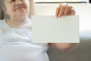 Happy elderly woman holding a blank paper card with copy space for the designer.