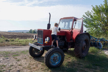 A boy is playing on a red tractor