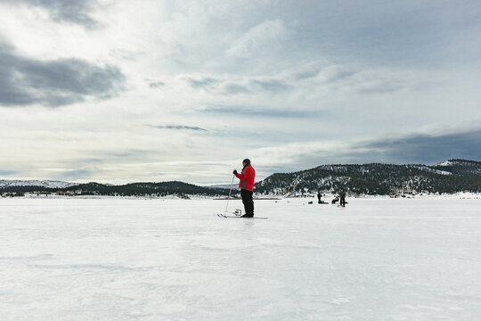 Family On Frozen Lake Ice Fishing And Cross Country Skiing