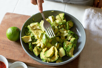 Boy using fork to mash sliced avacado