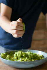 Boy in Blue Shirt Squeezing Lime into Guacamole