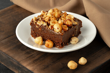 Fototapeta na wymiar Brownie cake with nuts topping on plate close up