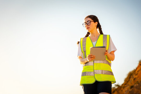 Inspection environmentalist. Bottom view of volunteer woman wearing vest and using pad for analyzing water. In background is sky. Copy space. Concept of air pollution and ecology