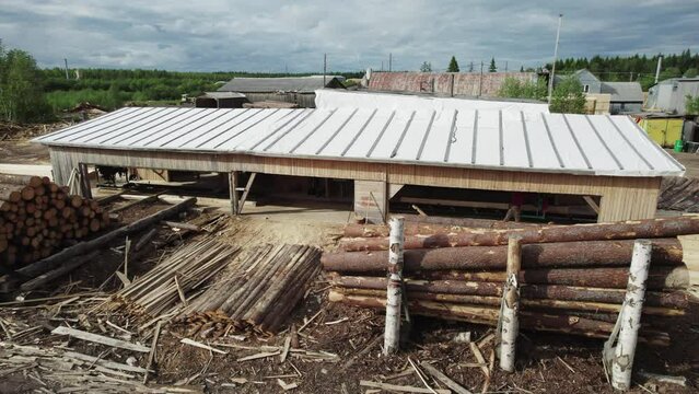 Small timber processing facility with a storage yard for roundwood and sawn timber, industrial wood processing site, Arkhangelsk Region, Russia.