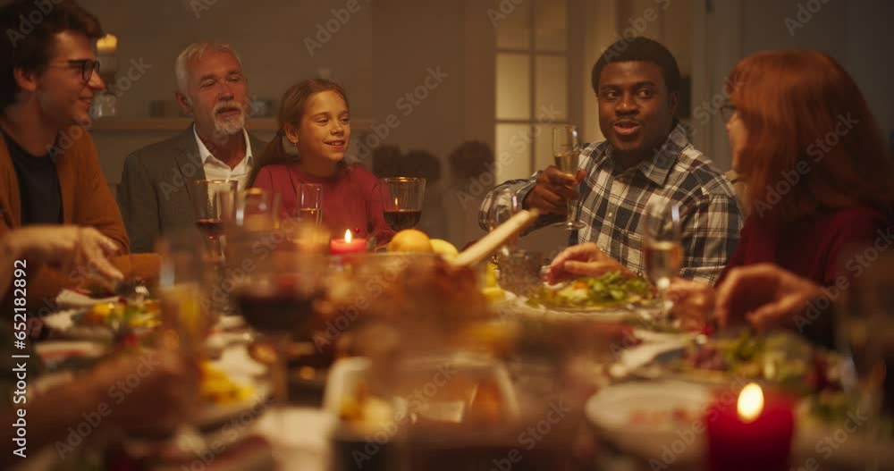 Wall mural Portrait of a Handsome Young African Man Proposing a Toast at a Christmas Dinner Table. Family and Friends Sharing Meals, Raising Glasses with Champagne, Toasting, Celebrating a Winter Holiday