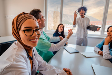 A medical team discussing at a meeting in the office a muslim female doctor in hijab smiling...
