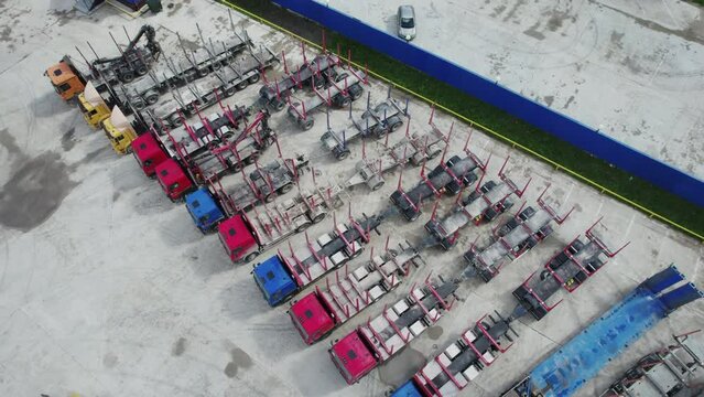 Parking area with trucks and trailers used for transporting roundwood at an industrial timber processing facility. Aerial view, Arkhangelsk Region, Russia.
