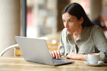 Amazed woman watching surprising content on laptop - 652187022
