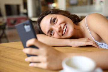 Obraz na płótnie Canvas Happy woman checking phone in a restaurant indoor
