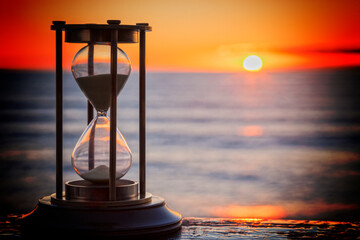 Sand Timer at Sunrise - Sand timer on a wooden ledge, looking out over a sunrise.