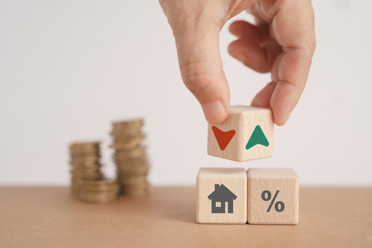 Real estate, investment concept house with percent on wood cube and hand flip block with up and down arrow sign and blurred coins, for increasing or decrease interest rates, tax interest, loan secured