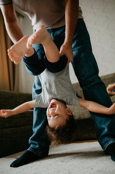 Father carrying son upside down at home