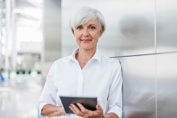 Portrait of smiling senior businesswoman holding tablet