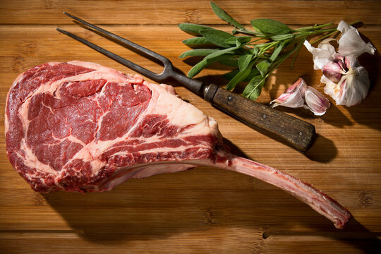 Raw tomahawk steak, garlic and herbs