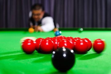 An action shot of a white snooker ball hits a group of red snooker balls. To start the game of...