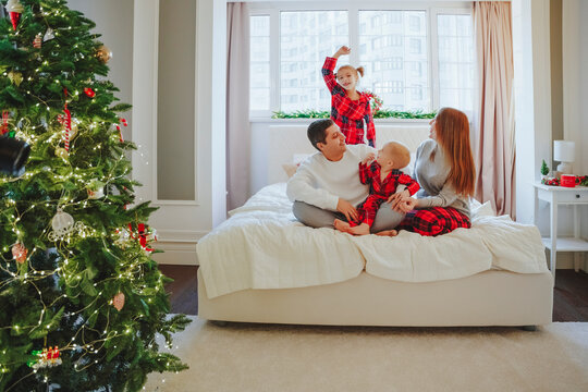 Family spending leisure time on bed near Christmas tree at home