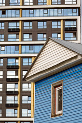 An old apartment building on the background of a new multi-storey residential building on an autumn day