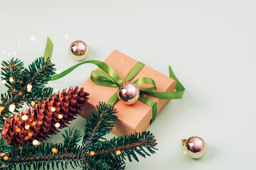 Christmas balls, fir branch and gift in a box on green background. Christmas festive layout. Top view, copy space