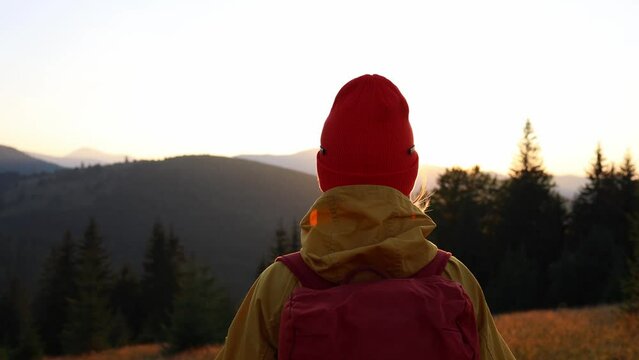 Free Happy Young Hiker Woman in yellow raincoat looking at view, enjoying calm sunset in nature, breathing fresh air. People Mountains Freedom Concept, Happiness