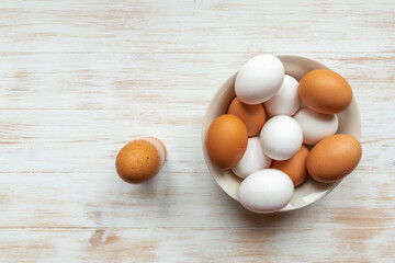 Free-range organic brown and white eggs in bowl and boiled egg in holder on vintage wooden background