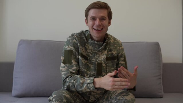 Headshot of handsome young military man adjusting hair and winking looking at camera smiling. Close-up portrait of confident Caucasian recruit soldier posing indoors. Confidence and military service.