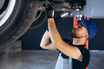 Auto mechanic lifting car and doing check up on car service