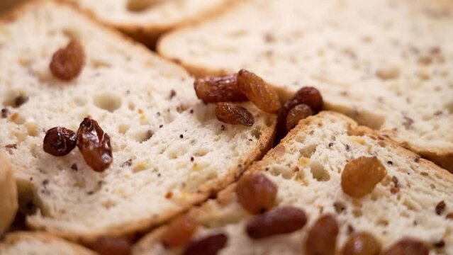Fresh cereal gluten free sliced bread with falling dried raisins close up. Slow motion. Healthy dietary food