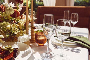 Sophisticated tableau arrangement on the table, adorned with candles and flowers beneath the play of shadows. A wedding style reminiscent of Provence aesthetics.
