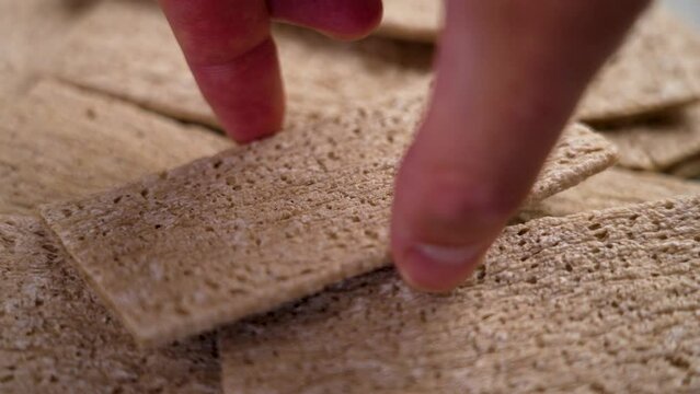 Hand takes healthy wholesome cracker from buckwheat close up. Gluten free crispbread