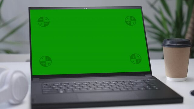  Modern Laptop Computer on White Desk with Blank Empty Green Mockup Screen
