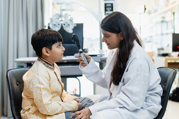 Indian child boy with women eye specialist examining eyesight modern ophthalmology equipment in clinic. Patient kid male checkup iris examines ophthalmological hospital. measure eyeglasses. - obrazy, fototapety, plakaty