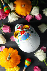 Mexican skull, zucchini and flowers on gray wooden background, top view