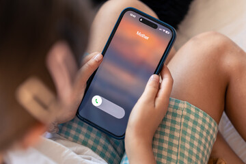 Smartphone in child hands with Incoming mother call on a screen.