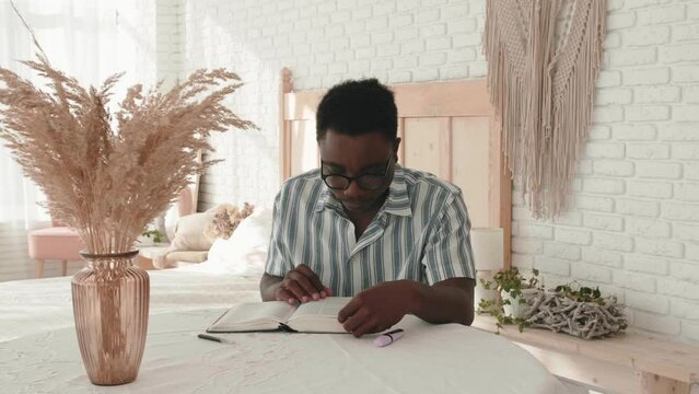 African black man reading bible. Fingers going line by line of the text. Reading Scripture, stydying, making notes with a pen. Religious class, learning bible stories, truth. The book. Student study 