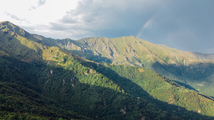 Aerial view of mountain slopes in summer with green fields and forest. Natural background, Italian...