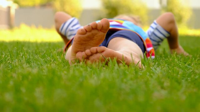 Child feet on the grass in the park. Selective focus.