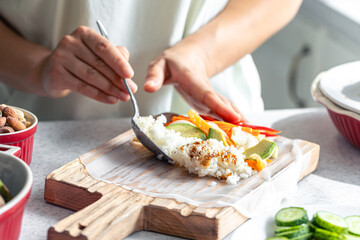 A woman making spring roll on cutting board.