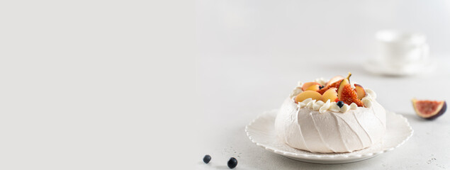 Meringue Pavlova cake banner. Anna Pavlova cake with peach, figs, blueberries and vanilla cream on a white background. Web line, copy space. Summer meringue dessert recipe, menu. Confectionery menu - obrazy, fototapety, plakaty