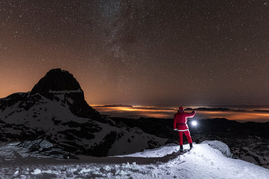 Christmas time image of Santa Claus holding lantern in snowy mountains