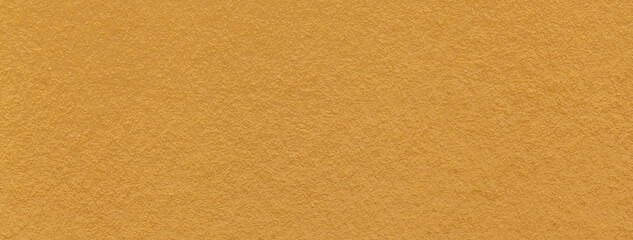 Texture of dark yellow and orange colors paper background, macro. Structure of dense ocher craft cardboard.