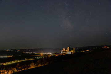 Starry night under the illuminated castle of Torrechiara in the Parma area.
