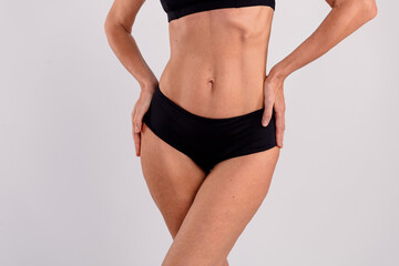 Closeup healthy fit slim body belly sportive elderly woman demonstrate black cotton lingerie posing...