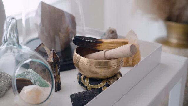 Woman's hands holding lit and smoking Palo Santo stick and preparing for yoga class by placing it in a Tibetan bowl